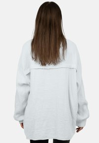 Witte oversized shirt van textuurstof, met lange mouwen en een rugnaadontwerp, voorzien van een subtiel gekreukt patroon.
