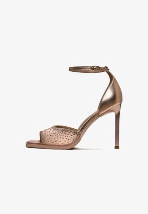 Offene High-Heels-Sandaletten mit metallic-finish, verziert mit kleinen klaren Kristallen im Obermaterial und einem schlanken Knöchelriemen.