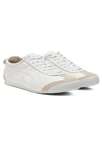 Hvide lædersneakers med beige ruskindsdetaljer, rund tå, flade snørebånd og tekstureret gummisål, der har et enkelt design og minimal branding.