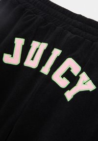 Zwarte joggers van stof met gedurfde, roze geborduurde "JUICY" letters omrand met groen op de achterkant. Zachte textuur en elastische tailleband.