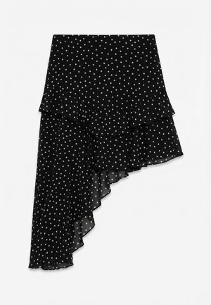 Μαύρη ασύμμετρη φούστα με λευκές πουά, βολάν σε στρώσεις στο τελείωμα και ρέον ύφασμα από σιφόν.