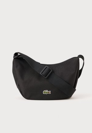 Black fabric shoulder bag with a curved shape, adjustable strap, and green embroidered crocodile logo. Durable material and smooth texture.