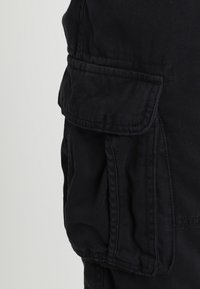 Pantalons cargo noirs avec une poche latérale à rabat, fabriqués en tissu durable, avec une coupe décontractée et un design à jambe droite.