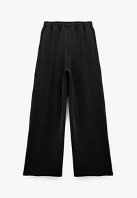 Pantalons larges noirs avec taille élastique, coupe ample, et texture de tissu lisse, posés à plat sur un fond blanc.