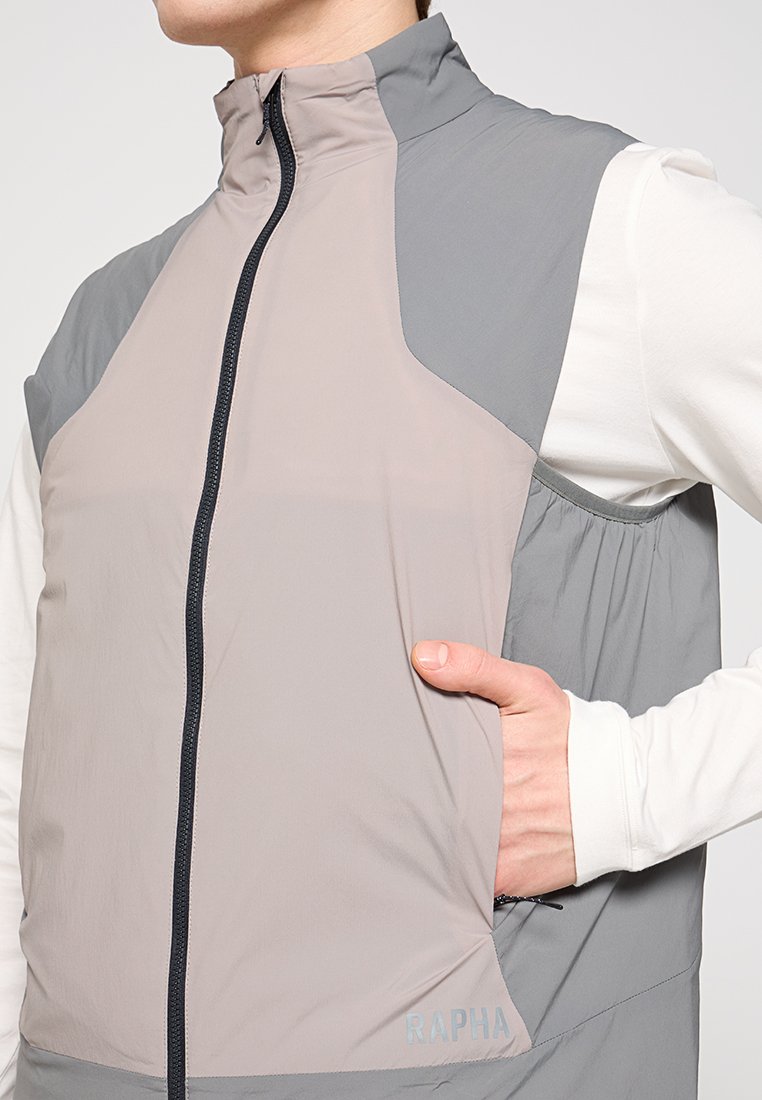 Leichte, graue und beige gefärbte Steppweste mit hohem Kragen, seitlicher Tasche und dem Markennamen auf dem Saum gedruckt.