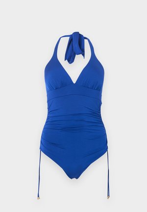 Μπλε ολόσωμο μαγιό με λαιμόκοψη halter, ραφές με σούρες στα πλάγια και ρυθμιζόμενους δεσιμους που κρέμονται σε απλό ανοιχτό φόντο.