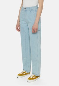 Ljusblå denim cargo-byxor med lös passform, med stora sidofickor och hög midja. I kombination med gula och vita sneakers.