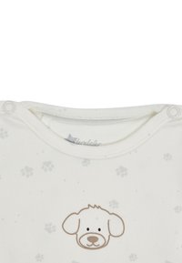 Weißer Baby-Body mit Druckknöpfen an den Schultern, kleinen grauen Pfotenabdrücken und einem einfachen Cartoon-Hundegesicht auf der Brust.