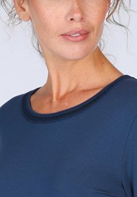 Navyblaues Oberteil mit rundem Ausschnitt und einem zarten strukturierten Saum. Glatte Stoffqualität, figurbetontes Design und dezente Details am Ausschnitt.