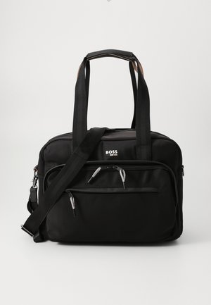 Svart nylon reiseveske med to håndtak på toppen og en avtakbar skulderreim. Har flere glidelåslommer og en logo på forsiden.
