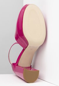 Tacchi alti in pelle verniciata rosa con punta arrotondata, suola piattaforma e cinturino alla caviglia. La suola è testurizzata e beige con logo.