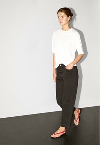 White short-sleeve t-shirt, black high-waisted pants, and pink flip-flops. Simple design with a relaxed fit and smooth fabric.