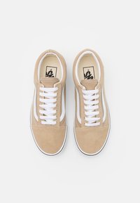Sneaker in suede beige con lacci bianchi, caratterizzati da una striscia bianca lungo i lati e una suola in gomma nera. Design a punta rotonda e piatta.