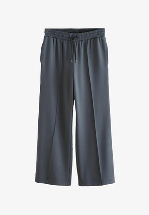 Ogļu pelēki platajā kārtā bikses, kas izgatavotas no gludas auduma. Tām ir elastīga jostasvieta ar auklu un sānu kabatām.