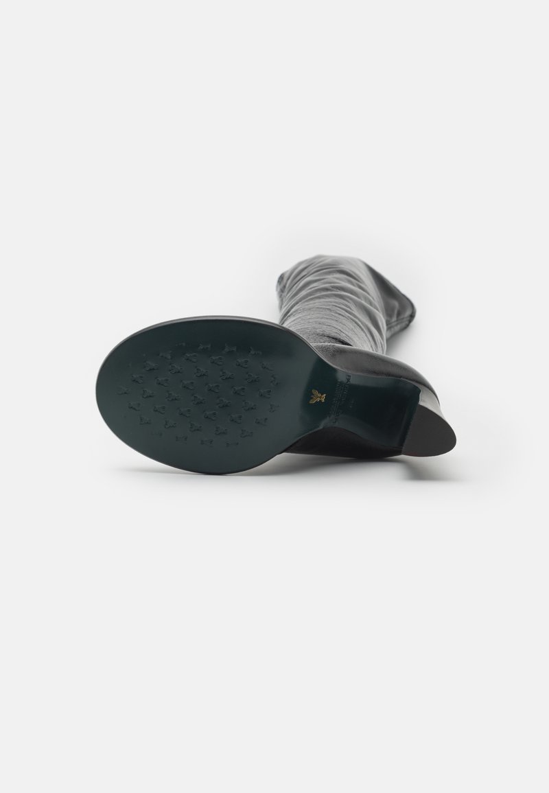 Czarne kozaki do kolan z gładką, teksturowaną cholewką, spiczałym noskiem i niskim, okrągłym obcasem. Podeszwa ma wzorzystą, antypoślizgową konstrukcję.