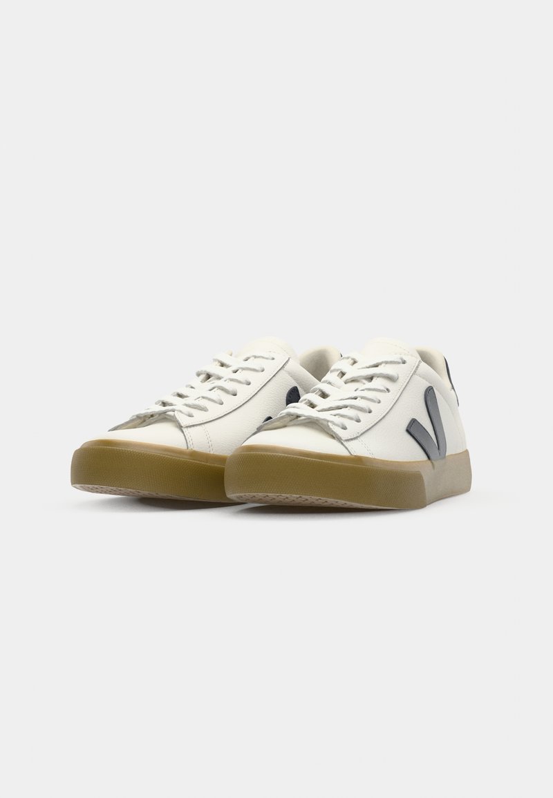 Des baskets blanches à tige basse présentent un dessus en cuir lisse, des accents en caoutchouc gris, un bout rond et une semelle en gomme solide. Les lacets sont blancs et plats.