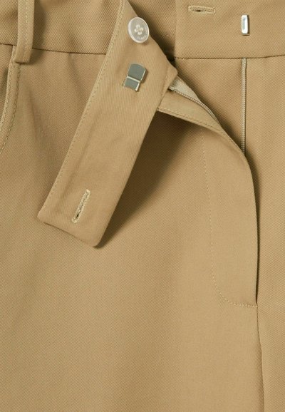 Pantaloni beige su misura con chiusura a bottone e clip in metallo, dotati di patta con zip e dettagli finemente cuciti su tutto il tessuto.