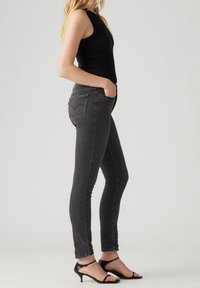 Smala svarta jeans med hög midja, femficksdesign och subtil blekning. Kombinationen med svarta remsandaler med klack.