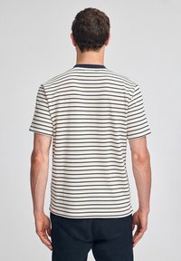Krótki rękaw, paskowana koszulka w kolorze kremowym z granatowymi poziomymi paskami, wykonana z miękkiej tkaniny, z okrągłym dekoltem i luźnym fasonem.
