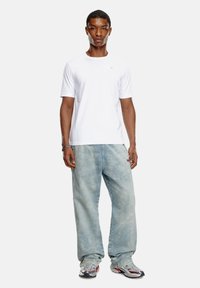 Hvid kortærmet t-shirt, løse lyseblå jeans og grå sneakers med røde accenter. Simpelt design, afslappet pasform og letvægtsstof.