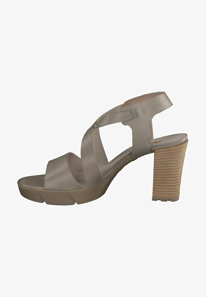 Beige nahka korkokenkä, jossa on ristikkäiset hihnat, kiinteä pohja ja uritettu puukorko. Sileä pinta ja minimaalinen yksityiskohtaisuus.