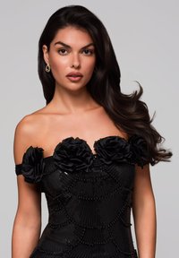 Černé bezramínkové šaty se třemi černými květinovými aplikacemi na výstřihu, zdobené flitry a korálky v texturovaném, zvlněném vzoru.