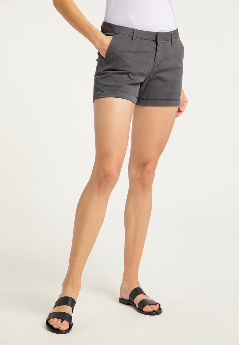 Harmaat puuvillahousut, joissa on istuva muotoilu, kaksi sivutaskua ja sileä tekstuuri, yhdistettynä mustiin liukusandaaleihin.