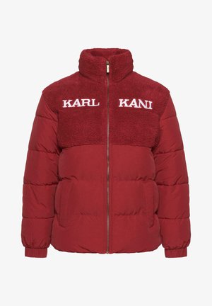 Punane puhvjakas kõrge kraega, tekstuuriga fliisist ülaosa, lukuga sulgemine ja valge broderylogo rinnal. Omab küljetaskuid.