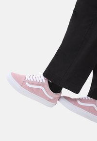 Zapatillas de ante rosa con cordones blancos y franjas laterales, que presentan un diseño de corte bajo y suelas de goma blanca a contraste.