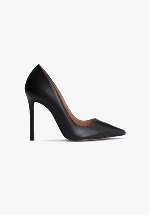 Sort læderhøjhælet sko med spids tå, stiletthæl og lavtskåret side, vist fra indersiden på hvid baggrund.
