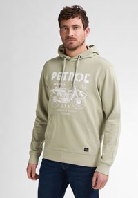 Sudadera verde claro con un bolsillo canguro, que presenta un gráfico de motocicleta blanca y un logotipo en texto. Fabricada con una tela suave y con un ajuste relajado.
