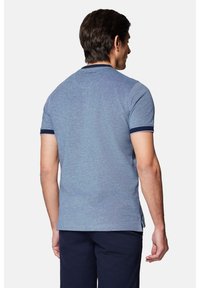 Niebieska, krótko rękawowa koszulka polo wykonana z fakturowanej tkaniny, z prążkowanym granatowym kołnierzykiem i mankietami, z bocznymi rozcięciami u dołu.