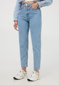 Jeans high-waisted blu chiaro con taglio dritto, caratterizzati da una finitura sbiadita, design a cinque tasche e chiusura con bottone metallico.