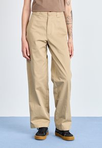 Pantaloni beige a gamba larga con vita alta, chiusura frontale con bottone e tasche laterali, realizzati in tessuto twill di cotone.