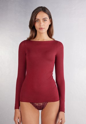 Burgundy långärmad topp i mjukt tyg med båthals. Har en figurnära silhuett som sträcker sig ner till höfterna.