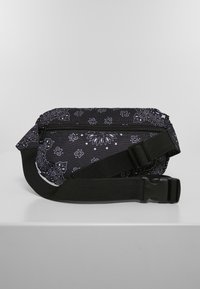 Borsa in tessuto nero con stampa paisley bianca, dotata di tasca con zip e tracolla regolabile. Texture liscia, design compatto.