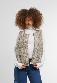 Leichte, ärmellose Weste in Beige mit einem subtilen Tiermuster. Verfügt über einen Reißverschluss an der Vorderseite und zwei große Fronttaschen. Weiches Stoffdesign.