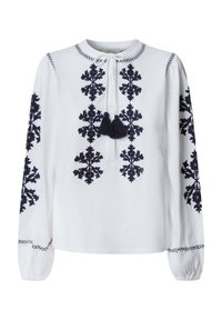 Blouse blanche à manches longues avec une broderie florale noire complexe sur le devant et les manches, dotée d'un col rond avec lien et pompons.