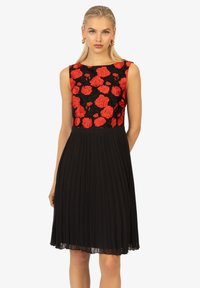 Abito nero a pieghe con corpetto aderente e ricami di rose rosse. Design senza maniche con scollo rotondo, tessuto fluido.