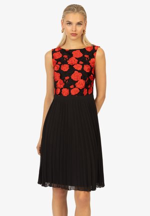 Schwarzes, gefältetes Kleid mit einem taillierten Oberteil, das mit roten Rosen bestickt ist. Ärmelloses Design mit Rundhalsausschnitt und fließendem Stoff. 