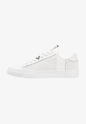 Weiße Sneakers mit perforierten Leder-Seitenpanelen, flachen Schnürsenkeln und einer strukturierten Gummisohle. Metallic-Akzente an der Ferse und Zunge.