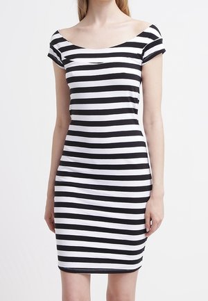 Femme portant une robe moulante à manches courtes, rayée horizontalement en noir et blanc, avec un large décolleté arrondi.