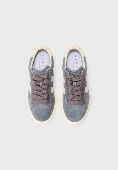 Een paar grijze suède sneakers met off-white accenten en dikke grijze veters, van bovenaf gezien op een effen witte achtergrond.