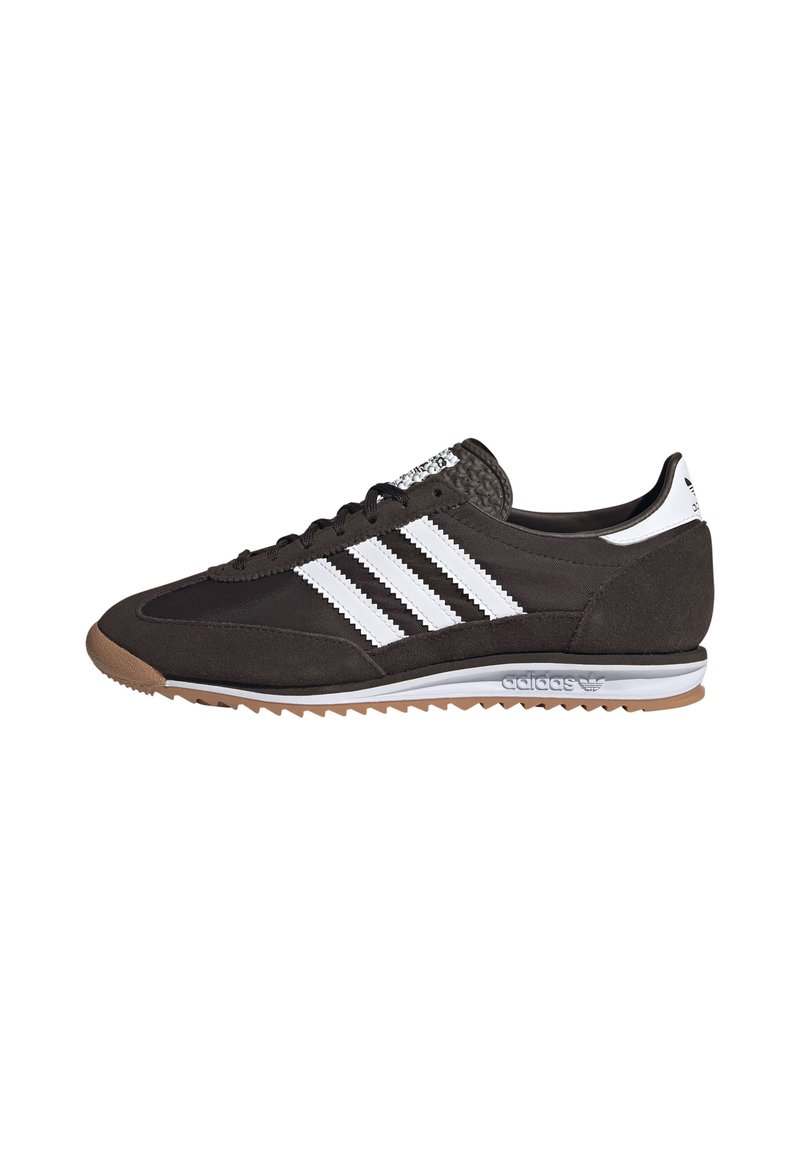 Sneaker nera in suede con tre strisce bianche, suola in gomma, tallone texturizzato e accenti grigi. Presenta un design con lacci e un profilo basso.