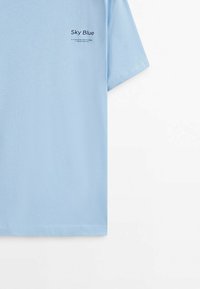Himmelblå bomulds T-shirt med korte ærmer, med sort trykt tekst "Himmelblå" på brystet. Glat tekstur, almindelig pasform.