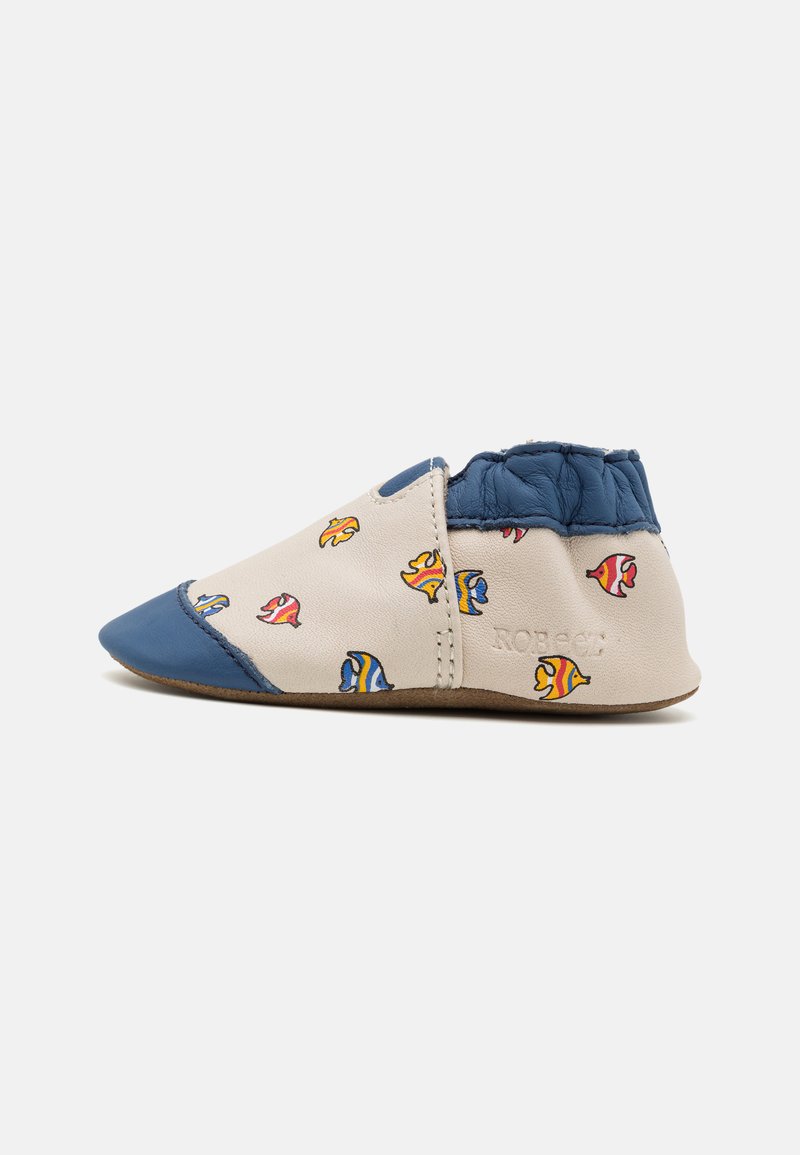 Scarpe slip-on per bambini in pelle beige con dettagli blu, caratterizzate da un motivo di pesci colorati. Design morbido e flessibile con punta arrotondata.