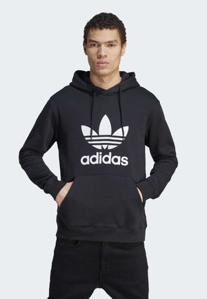 Zwarte katoenen hoodie met een kangoeroezak, capuchon met trekkoord en een groot wit Adidas-logo met drie strepen op een bladontwerp.