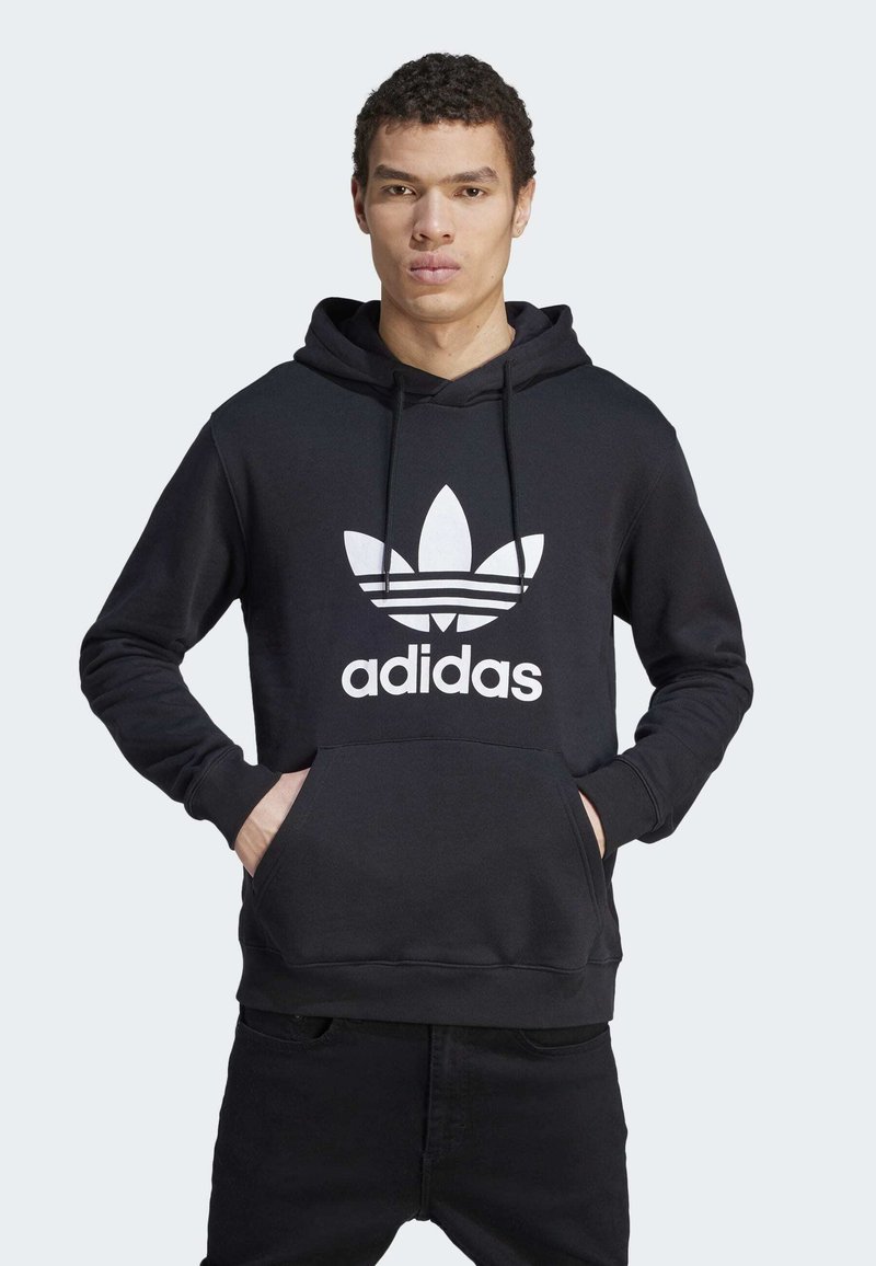 Crna pamučna dukserica s kenguruh džepom, kapuljačom s uže, i velikim bijelim Adidas logom koji sadrži tri pruge na dizajnu lista.