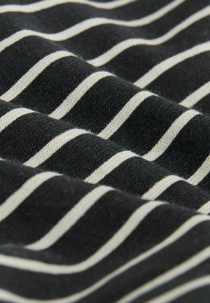 Sort stof med jævnt spaced vandrette hvide striber, der viser bløde folder og strikket tekstur i nærbillede.