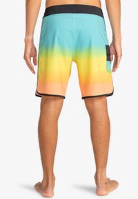 Costumi da bagno da uomo in gradiente di blu, verde, giallo e arancione. Caratterizzati da una vita nera e una tasca laterale. Tessuto morbido.